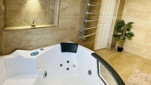 A bathroom with a white bathtub, a towel rack, a potted plant, and a shower area. - Cozy Room in Fratton: Featuring Hot Tub, Kitchen & Free WiFi (Fratton)