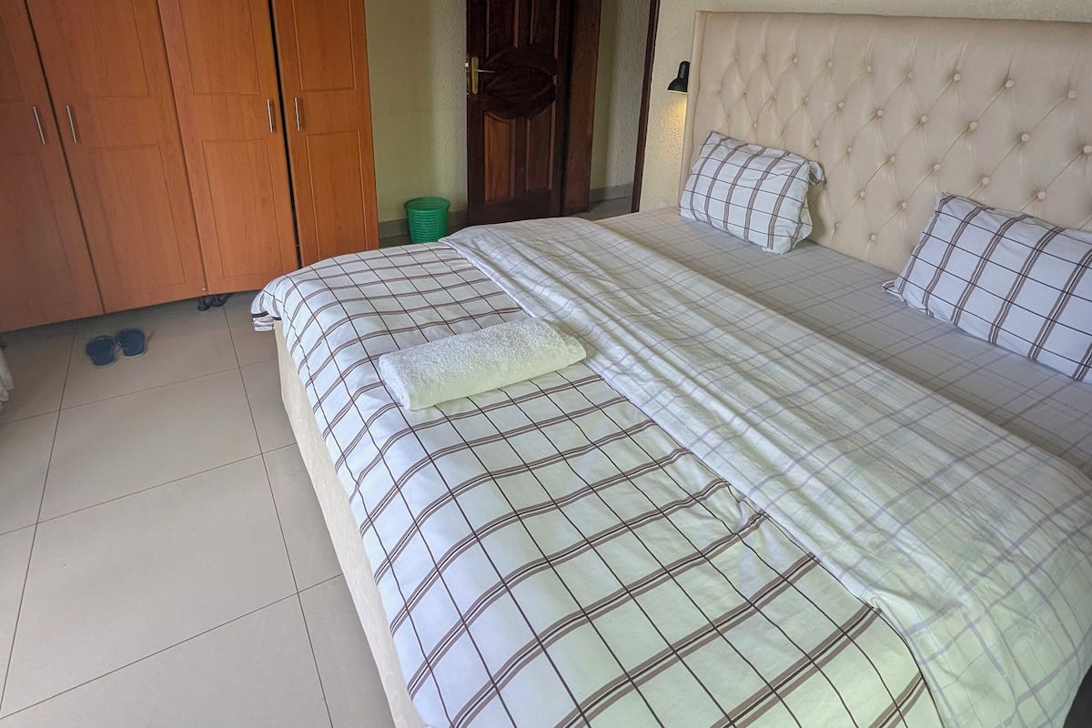 Un dormitorio con una cama grande, un armario de madera y una puerta con un panel decorativo.