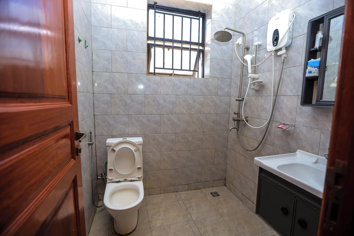 Un baño con inodoro, ducha, lavamanos y ventana.
