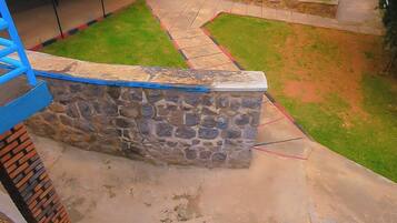 A stone wall, a concrete patio, and a grassy area with a tree.