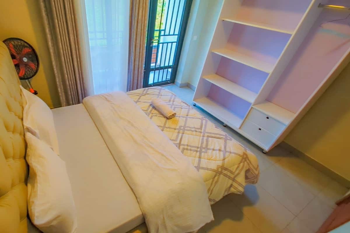 Un dormitorio con cama, sofá, ventilador y estantería.