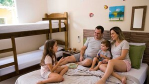 A family on a bunk bed with a small table, a painting, and a mirror on the wall.