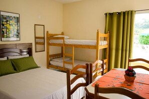 A room with bunk beds, a single bed, a dining table with chairs, and a window with curtains. - Recanto Soga Chalés (Ubatuba)
