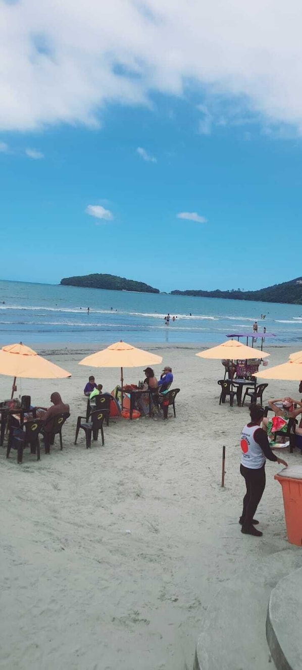 Un restaurant situĂ© en bord de mer, avec une terrasse et des parasols, offrant une vue sur lâocĂ©an.