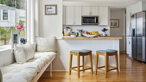 A modern kitchen with white cabinets, a built-in microwave, and a stainless steel refrigerator. - Boothbay Harbor King Suite - Room 4 at Greenleaf Inn - Fireplace, Harbor Views! (Boothbay Harbor)
