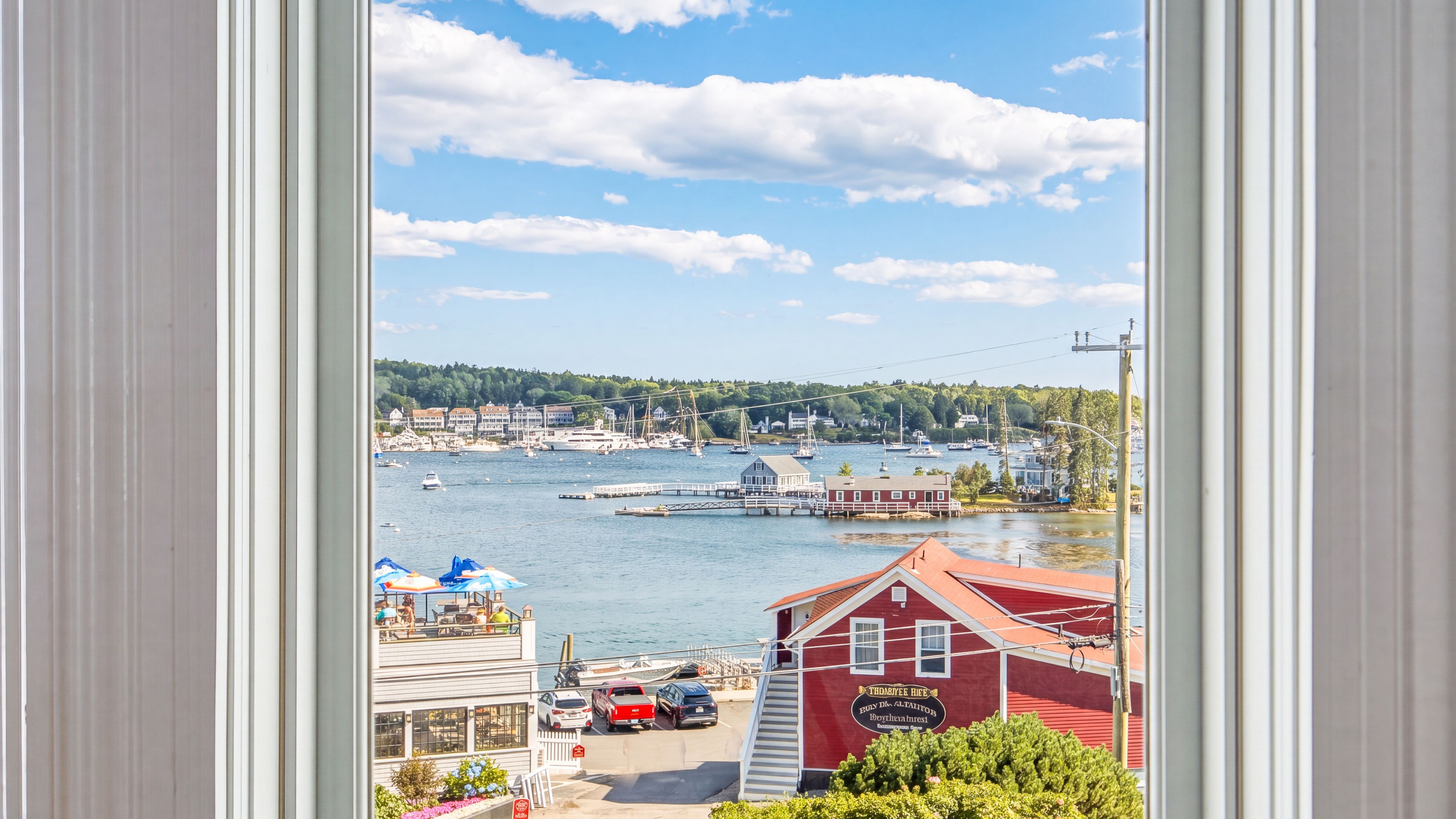 A coastal town with a marina, docked boats, and a red building with a sign.