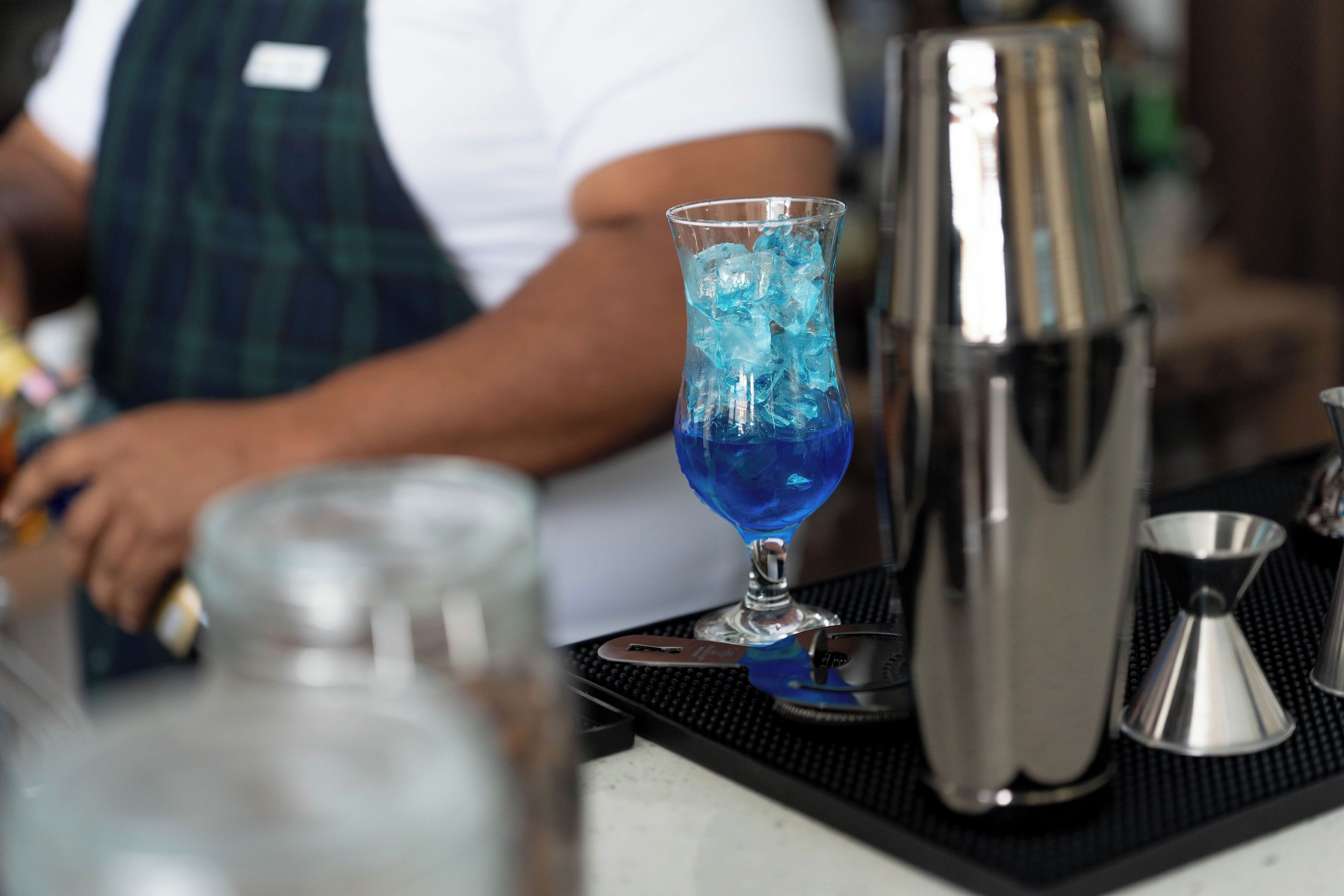 Una barra equipada con una copa de cóctel, un agitador y un tapete para bar.