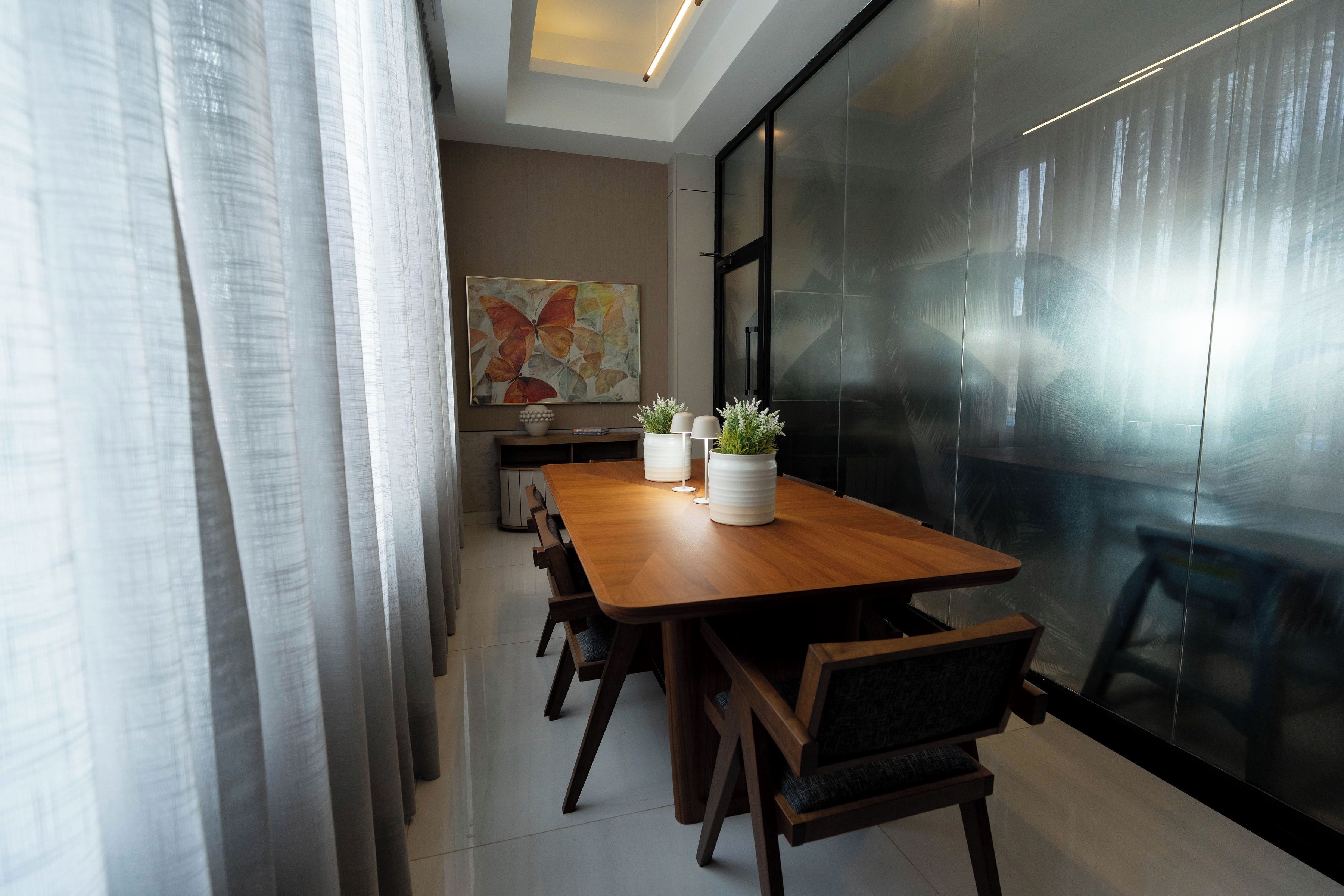 Une salle de réunion moderne, avec une table en bois, des chaises, des plantes en pot et un grand tableau abstrait accroché au mur.