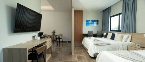 A modern hotel room with a flat-screen TV, a desk with a chair, two beds, a wooden headboard, and a large window with curtains.