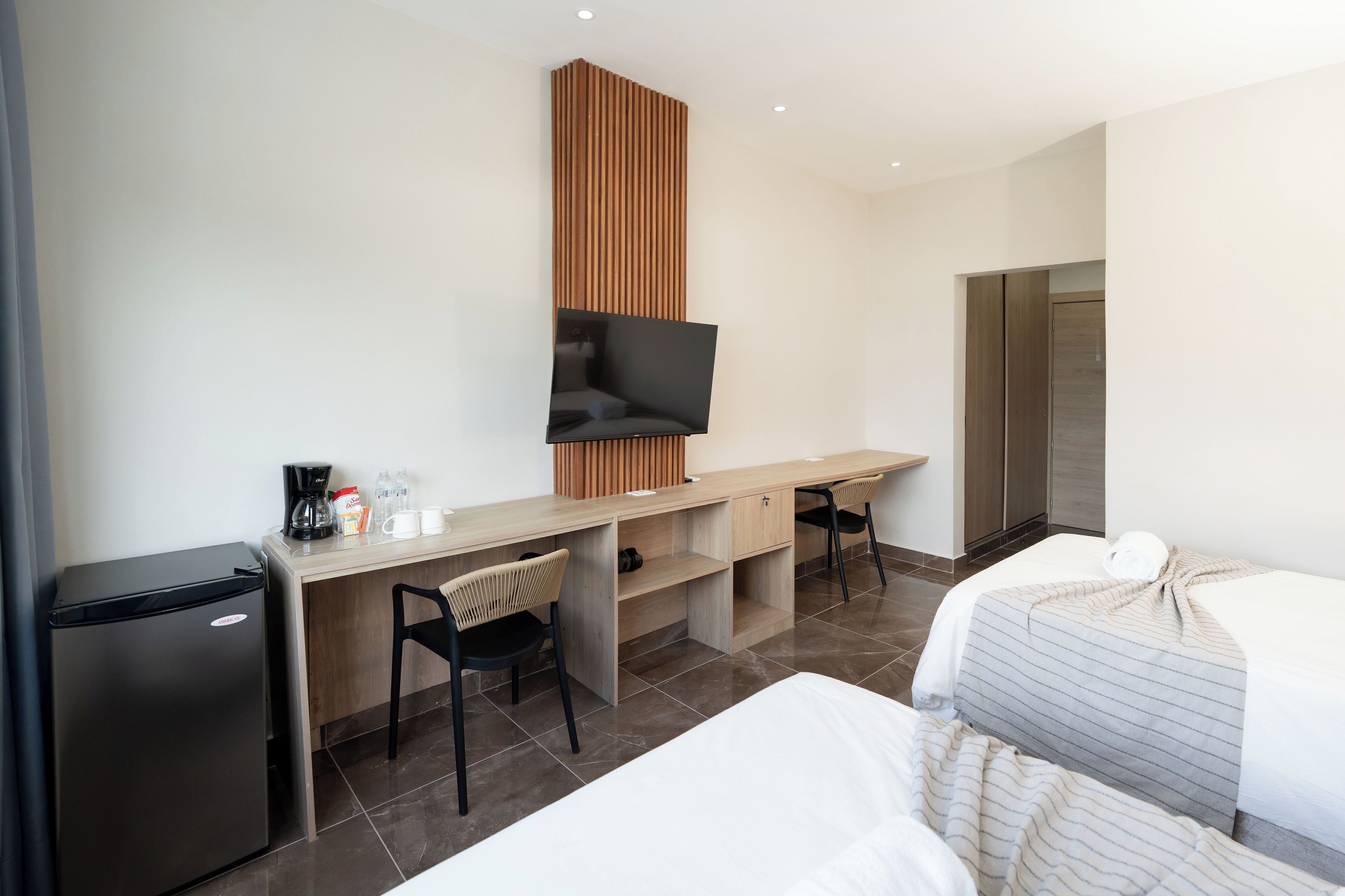 Hotelkamer met een bed, een bureau met stoel, een aan de muur bevestigde televisie, een koelkast en een kledingkast.