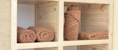 A wooden shelf unit with neatly rolled brown towels.