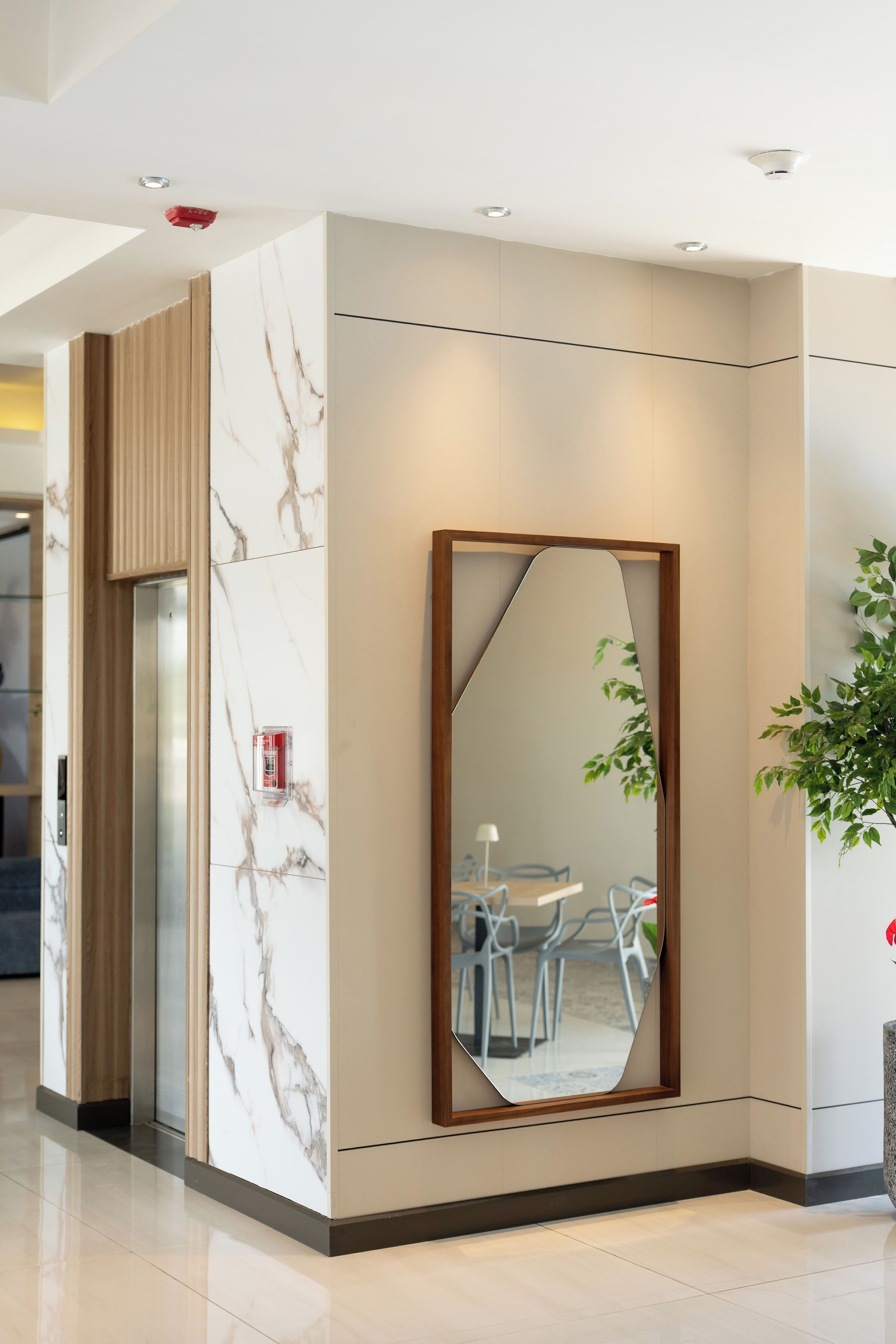 A modern elevator with a marble wall and a large mirror.