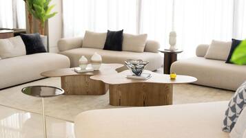 A modern living room with a beige sofa, two wooden coffee tables, and a glass vase.
