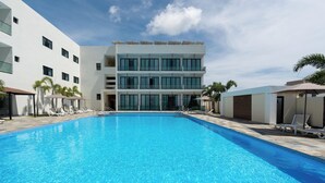 Um edifício moderno com piscina, espreguiçadeiras e guarda-sóis.