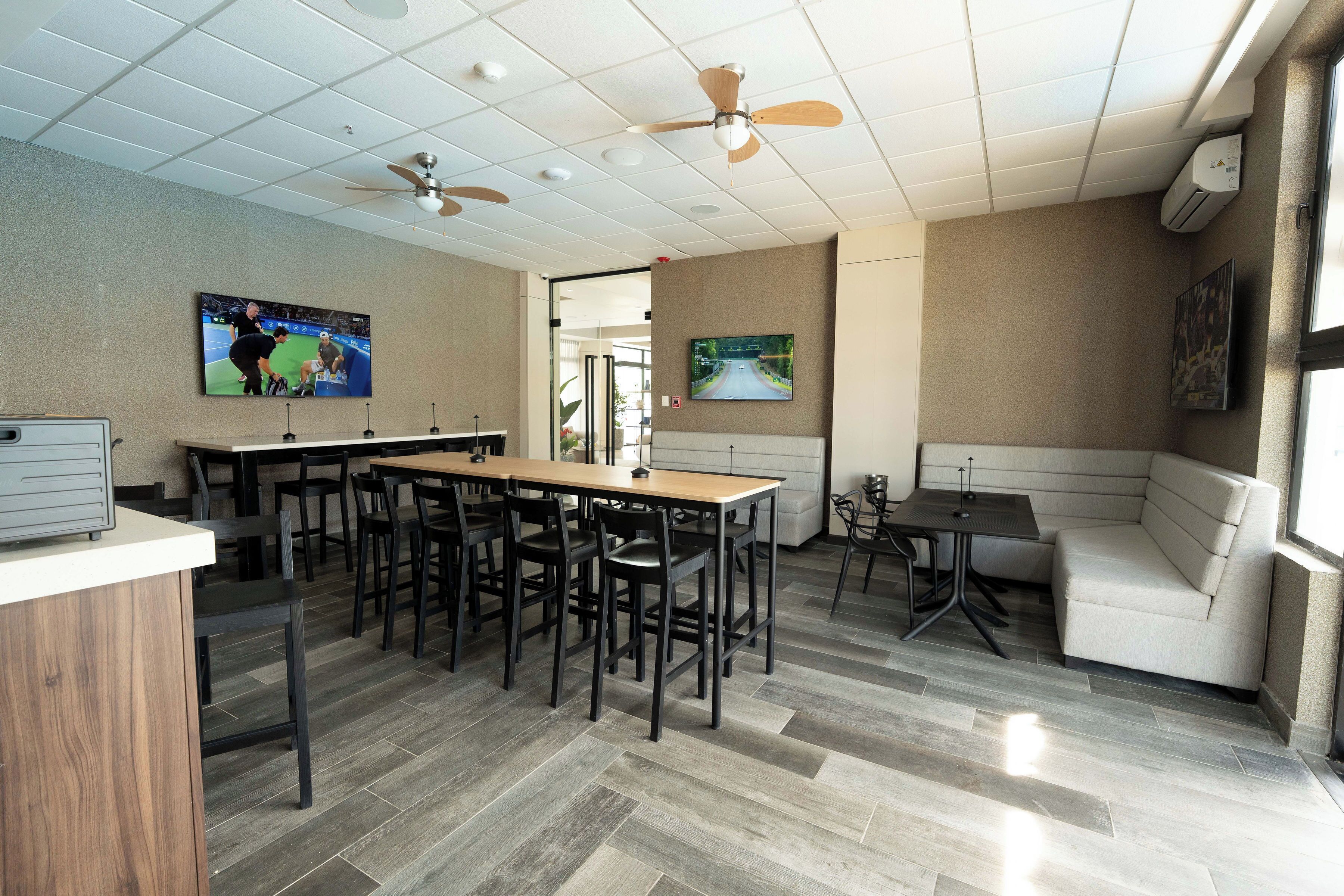 A conference room with a long table, multiple chairs, ceiling fans, and a large window.