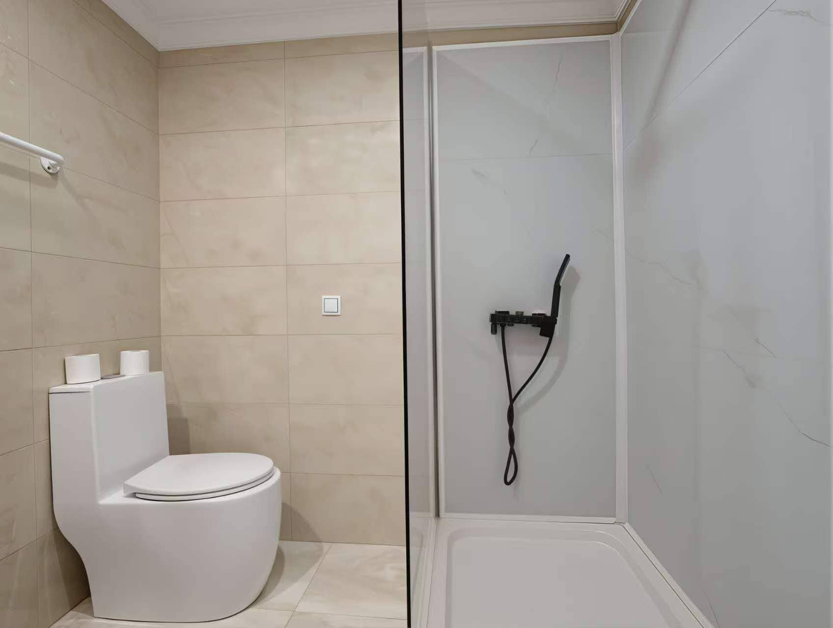 Un baño moderno con inodoro, ducha y mampara de vidrio.