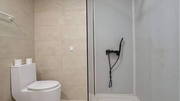 Un baño moderno con inodoro, ducha y mampara de vidrio.