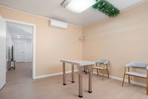 Une pièce comprenant une table, deux chaises, une porte et un appareil de climatisation.