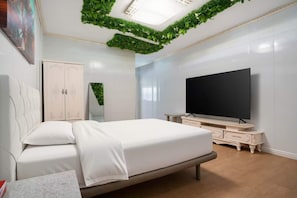 Une chambre à coucher avec un lit, une télévision, une armoire et un miroir.