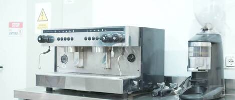 A commercial kitchen with a coffee machine and a large espresso machine.