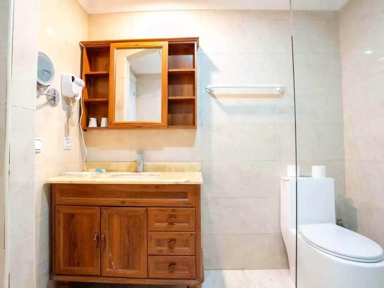 Un baño con tocador de madera, un espejo, toallero y un inodoro.