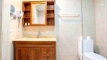 Un baño con tocador de madera, un espejo, toallero y un inodoro.