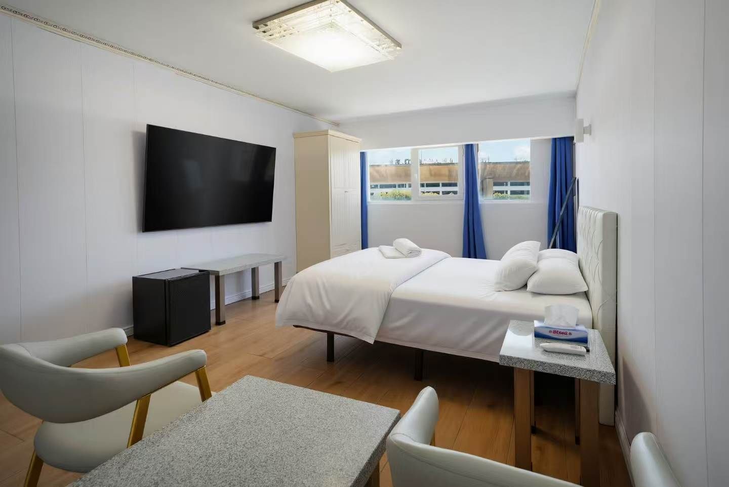 Una habitación de hotel con una cama, un televisor, un escritorio y una silla.