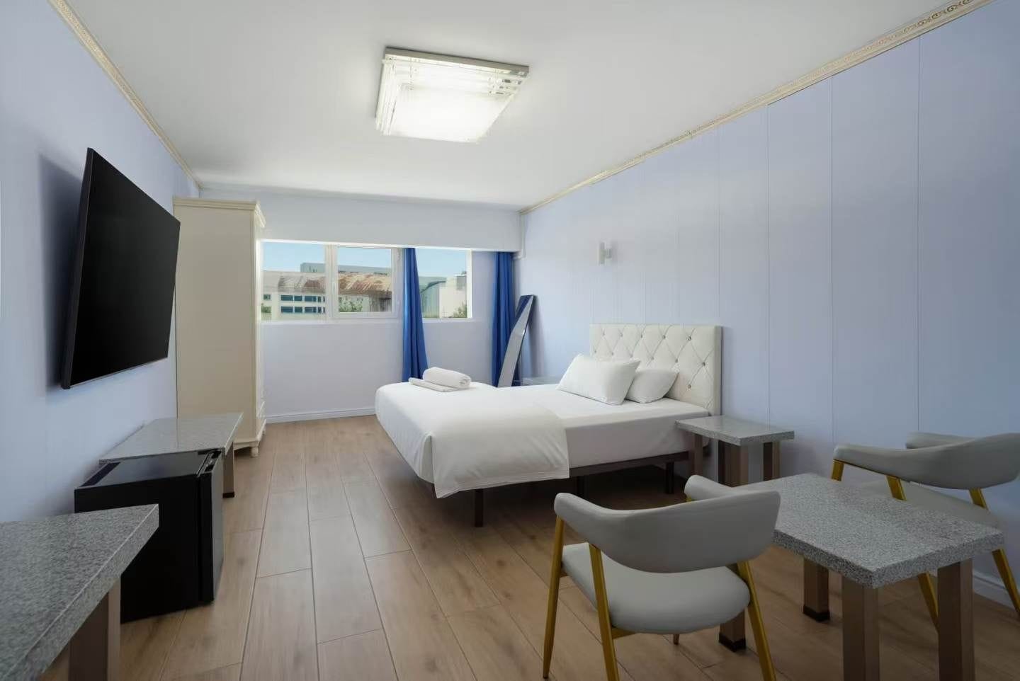 Une chambre d’hôtel comprenant un lit, des tables de chevet, un bureau, une chaise et un téléviseur.