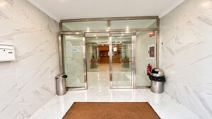 A hotel lobby with marble flooring, a reception desk, and a glass door entrance. - air hotel aviacion  (Manises)