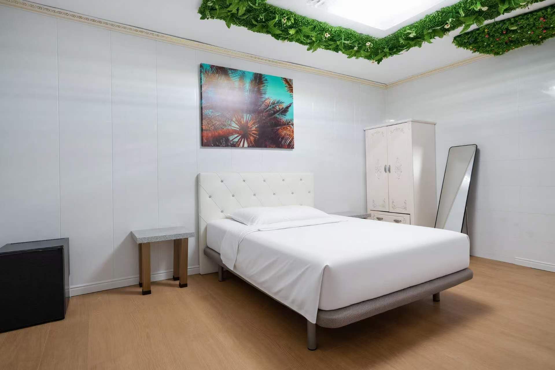 Une chambre à coucher avec un lit, une table de chevet, une armoire et un miroir.