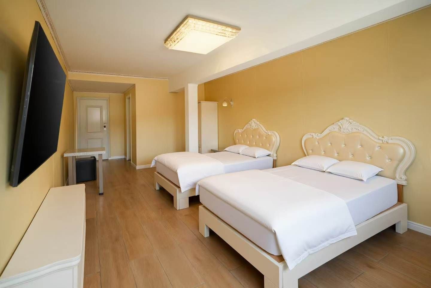 A hotel room with two beds, a TV, and a small table.