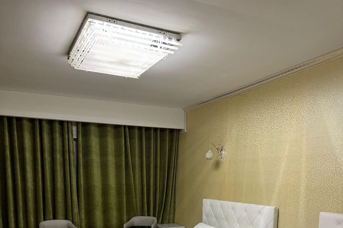 Habitación de hotel con dos camas individuales, un escritorio, una silla y un ventanal con cortinas.