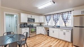 Una cocina compacta con armarios blancos, microondas, horno, lavabo y refrigerador.