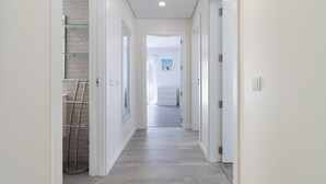 Un pasillo estrecho y bien iluminado con diseño moderno, que conduce a un cuarto de baño con ducha.