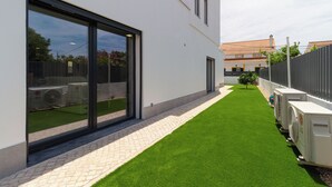 Un edificio moderno con amplios ventanales, un camino pavimentado y unidades de aire acondicionado.