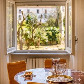 A dining table with a view of a garden through a window. - Apartment with large garden in Sorrento (Sorrento)