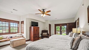 A bedroom with two beds, a ceiling fan, a TV, and a window seat. - Waterside Villa- 2BR-2B in Cuscowilla (Eatonton)