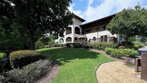 A building with a white facade, arched windows, and a balcony. There is a well-maintained lawn and a gravel path leading to the entrance. - Waterside Villa- 2BR-2B in Cuscowilla (Eatonton)