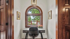 A room with a desk, a chair, a window with an arched top, and wooden doors. - Waterside Villa- 2BR-2B in Cuscowilla (Eatonton)