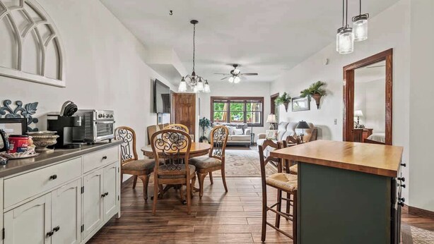 A spacious kitchen with wooden cabinets, a dining area with wooden chairs, a large island, and a ceiling fan. - Waterside Villa- 2BR-2B in Cuscowilla (Eatonton)