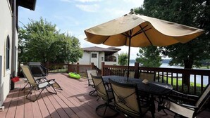 A wooden deck with outdoor furniture, including chairs and a table, and a large umbrella providing shade. - Waterside Villa- 2BR-2B in Cuscowilla (Eatonton)