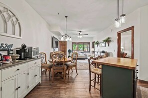 A spacious kitchen with wooden cabinets, a dining area with wooden chairs, a large island, and a ceiling fan. - Lakefront Villa w/Decks & Boat Slip in Cuscowilla (Eatonton)