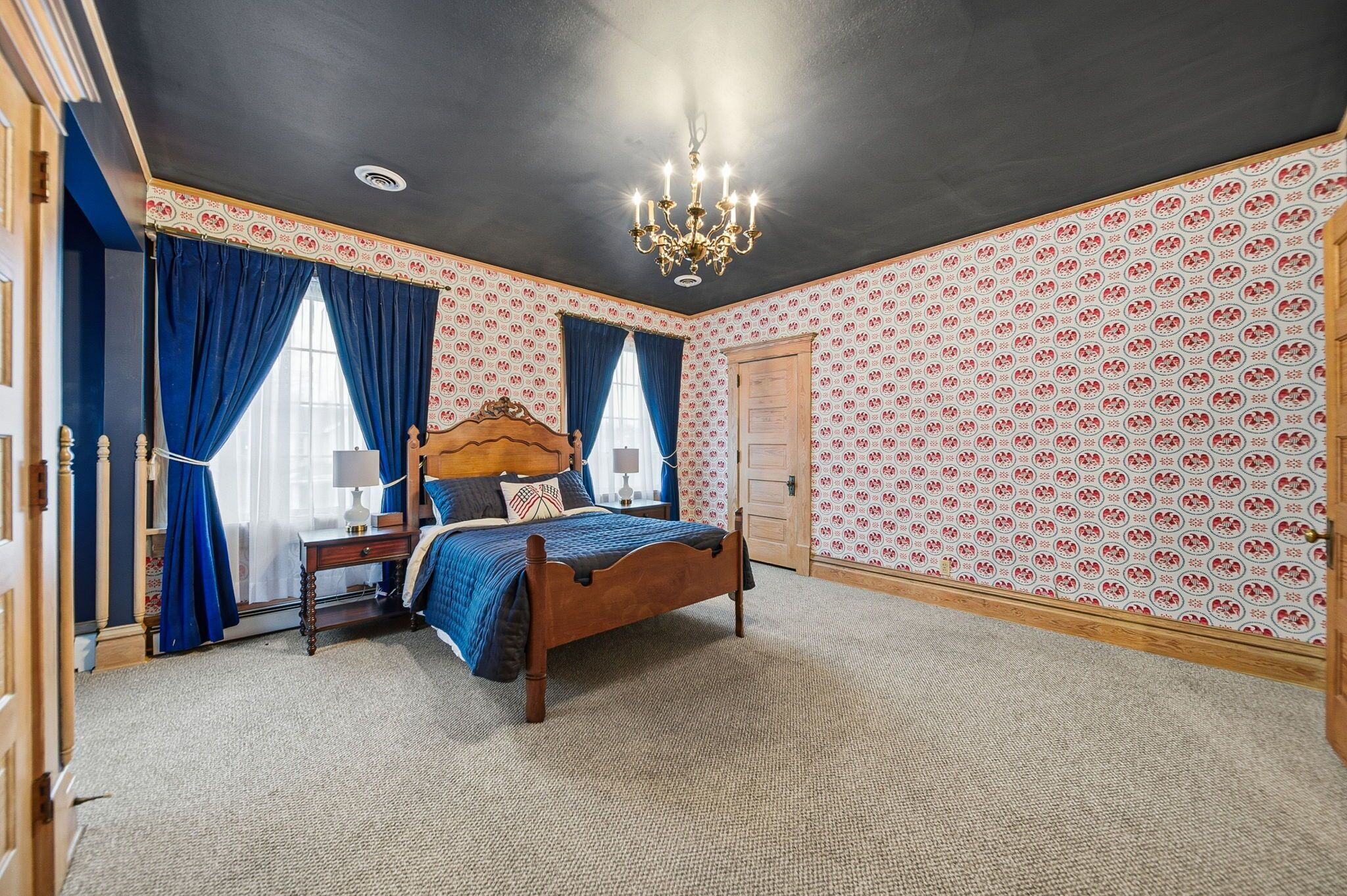 Een slaapkamer met een houten bed, een kroonluchter en behang met een patroon.