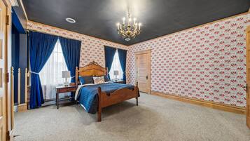 Een slaapkamer met een houten bed, een kroonluchter en behang met een patroon.