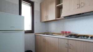 Une cuisine avec des meubles de couleur bois clair, un évier en acier inoxydable et une cuisinière à gaz.