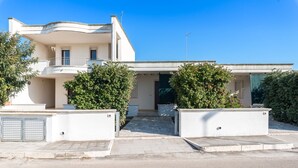 Un bâtiment moderne à deux étages, doté d’un toit plat, d’un balcon à l’étage supérieur et d’un espace d’entrée abrité.