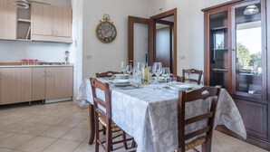 Un coin repas avec une table dressée pour quatre personnes, une horloge au mur et des meubles de rangement en bois.