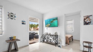 A spacious living area with a large TV, a console table, and a view of the outdoors.