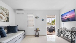 A modern living room with a grey sofa, a small table, and a TV on the wall.