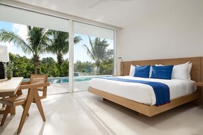 Ein Schlafzimmer mit einem großen Bett, einem Schreibtisch und einem Stuhl, sowie eine große Schiebeglastür, die zu einem Poolbereich führt.
